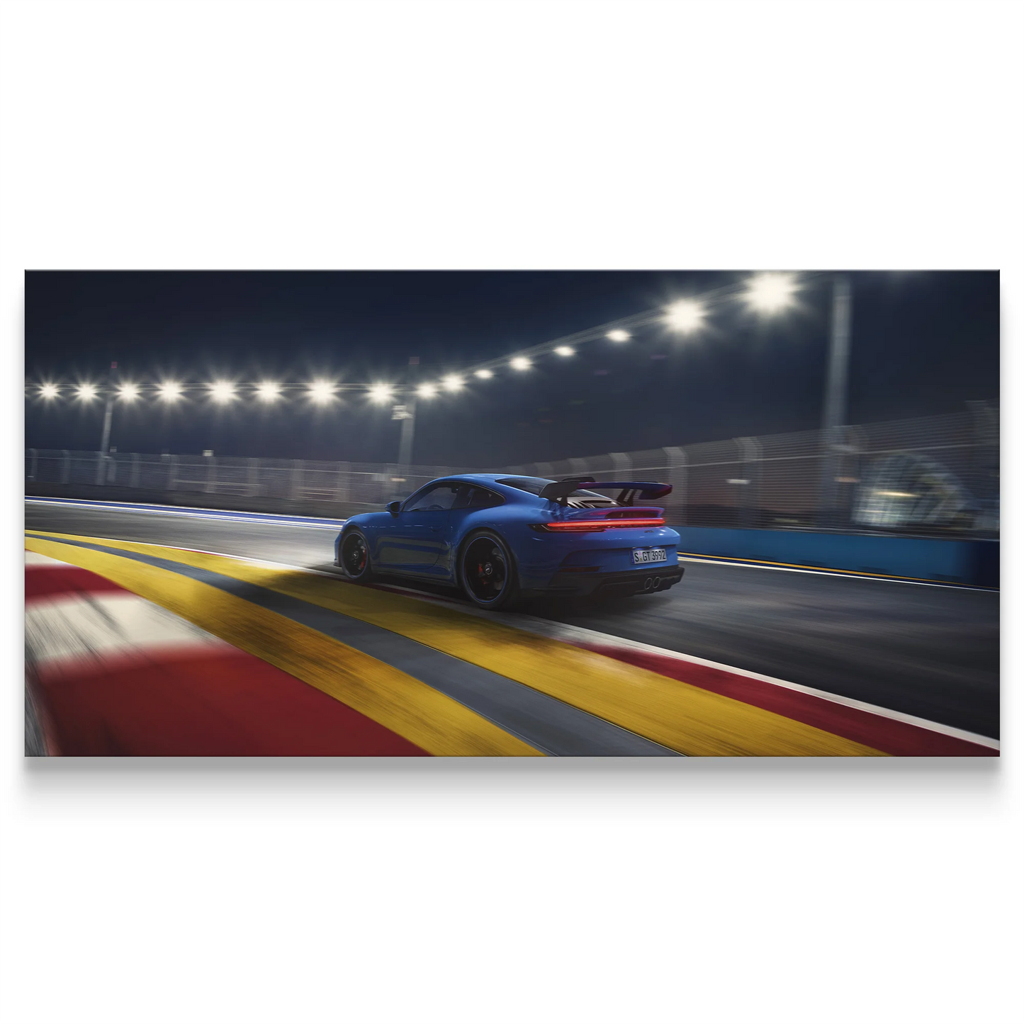 Blue sports car on a race track at night with illuminated lights.